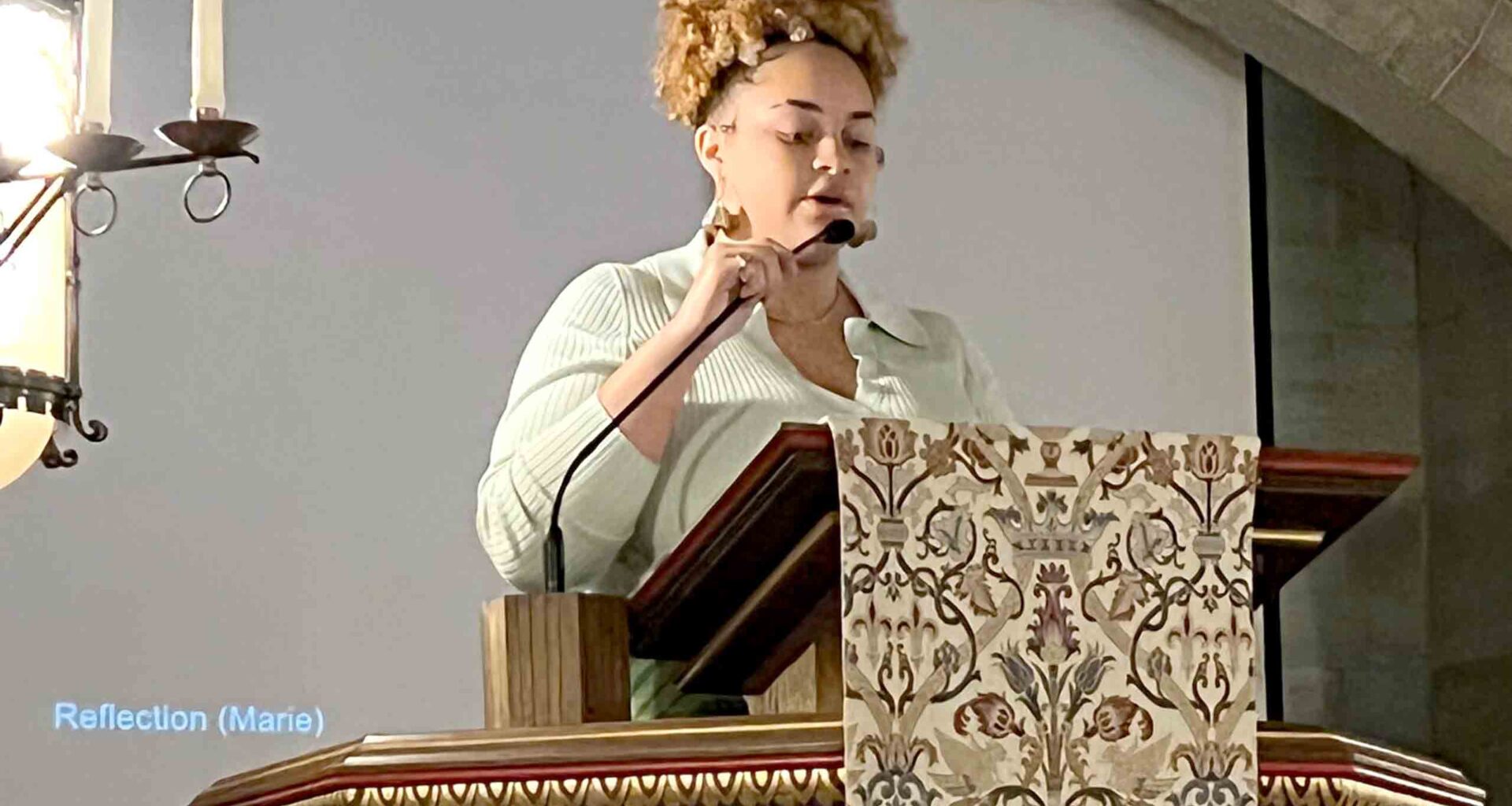 Young woman speaking from a podium in a chapel