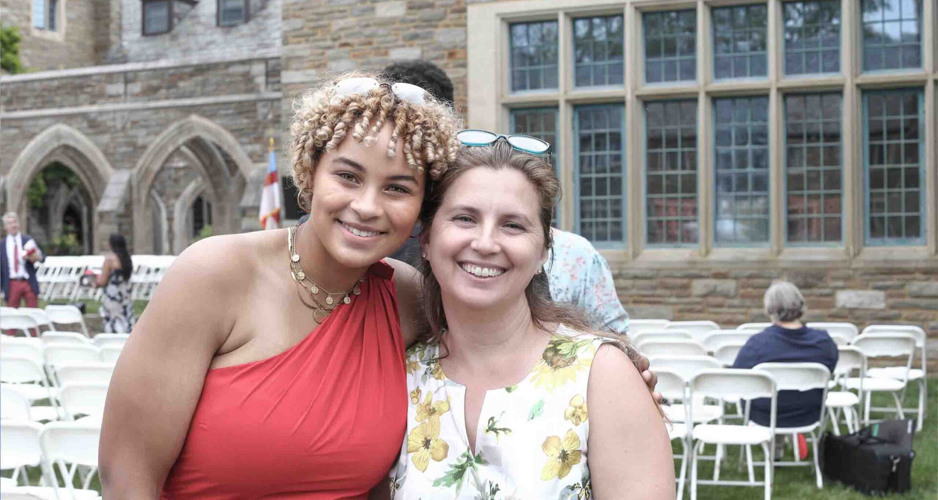 Marie in a red dress and Ms. Klecan in floral dress side-by-side embracing for a candid photo memory after Commencement at St. Andrew's School May 2023.