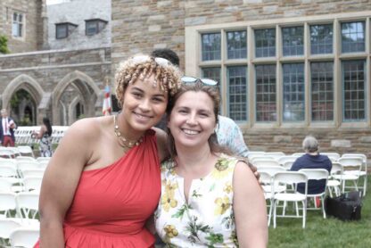 Marie in a red dress and Ms. Klecan in floral dress side-by-side embracing for a candid photo memory after Commencement at St. Andrew's School May 2023.